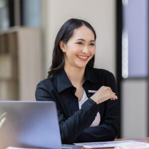 Female account manager checking document using laptop in office,