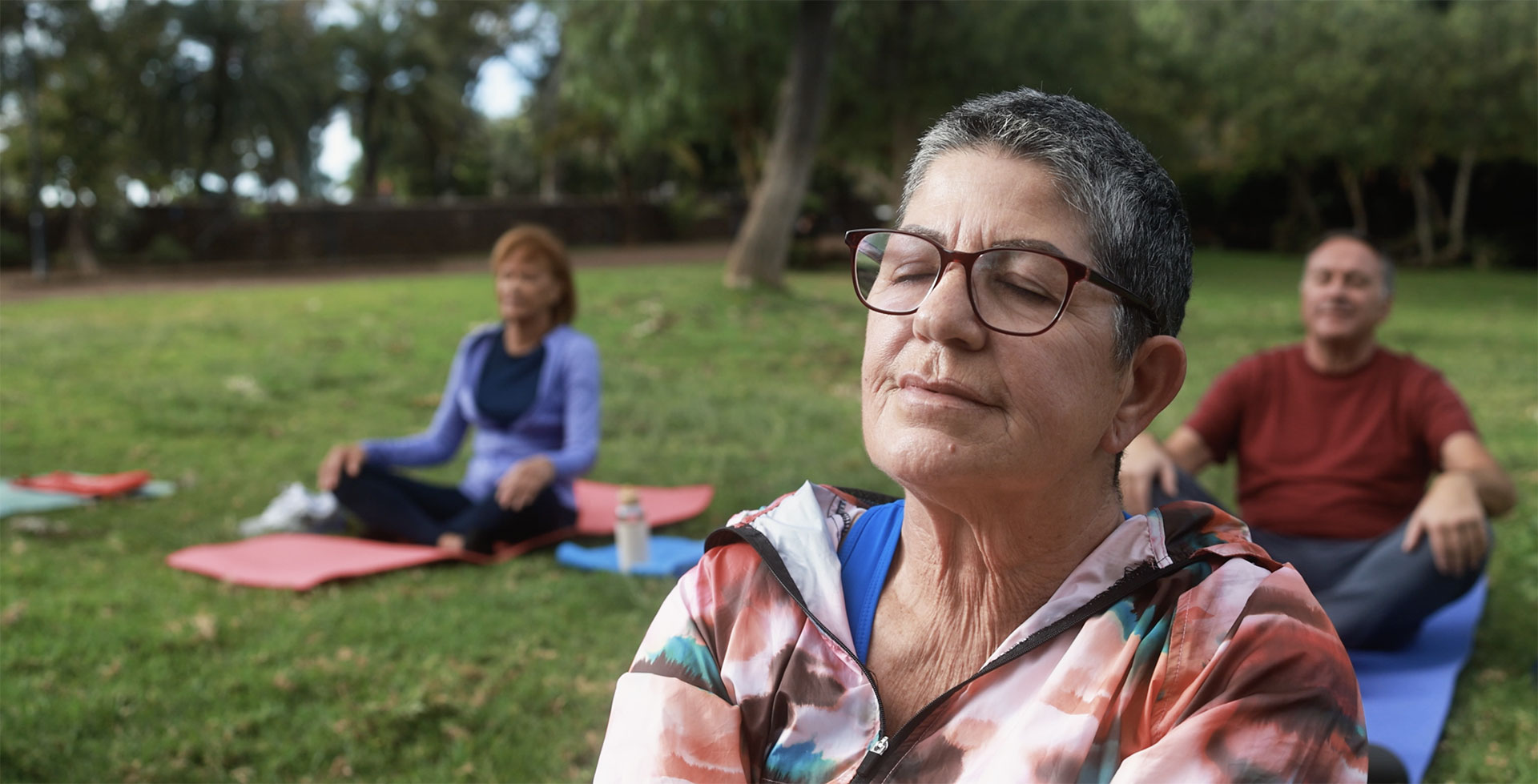 Group-of-seniors-meditating-on-lawn-of-park